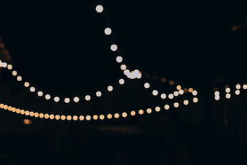 Decorative outdoor string lights at night time, Defocused Background, night city life backdrop,...