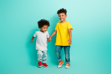 Full size photo of two adorable small boys friendly brothers hold hands have fun wear trendy outfit...