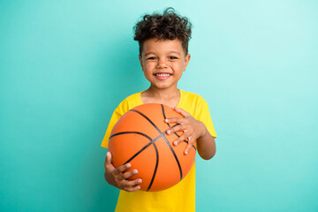 Photo of good mood positive schoolboy with brown hair dressed yellow t-shirt hold basketball ball...
