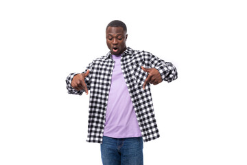 handsome young african man with short haircut in a plaid shirt shows his hands to the promotional offer