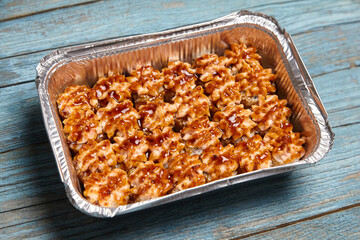 Baked sushi rolls in a baking dish on blue wooden background. Hot sushi rolls with different kind of fish and fillings. Tempting view of baked sushi