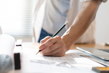 architect work concept. Close up hand of architect writing on the blueprints in the office.