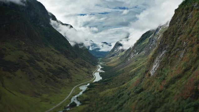 An aerial view of the narrow valley between the mountains. a river and a road wind through the valley.