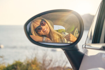 Blonde woman with sunglasses looking at herself in the mirror of