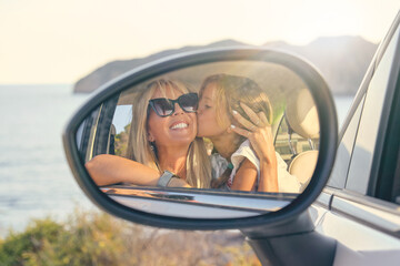 Car mirror with the image of a blond daughter kissing her mother