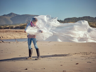 Kid with flattening white plastic film on beach