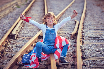 Happy boy with American flag on railroad