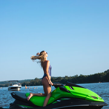 Side portrait of beautiful and sensual woman posing on the beach in summer in bikini on a jet ski 