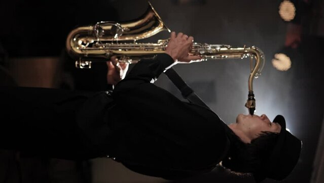 Man plays saxophone. Side view of saxophonist enthusiastically playing melody. Vertical video
