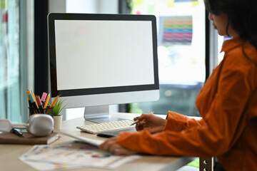 Side view of young woman having some creative work, sketching on a graphic tablet while working at cozy workplace.