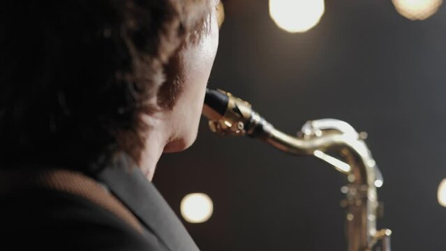 Saxophonist, jazz musician. Close-up view of saxophonist face from back