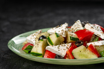 Greek salad with feta cheese, tomato, cucumber and olives  on a black background