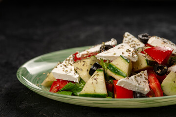 Greek salad with feta cheese, tomato, cucumber and olives  on a black background