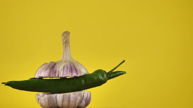 rotating young garlic with hot pepper inside on a yellow background.Copy space. place for text