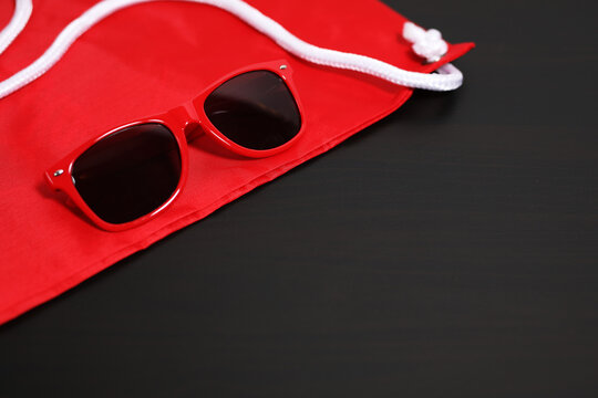 Red sunglasses lying on a red sport sack bag, on black background.