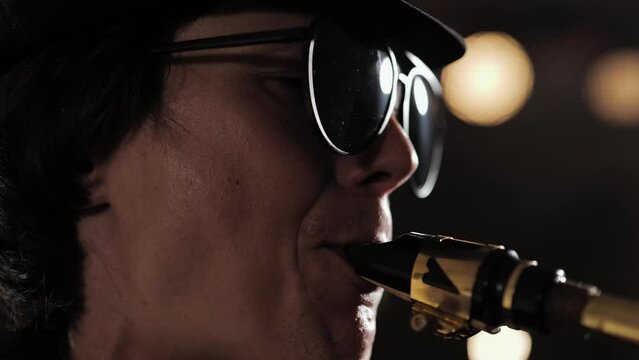 Saxophonist. Face of man with glasses and hat playing saxophone. Close-up