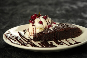 Chocolate brownie with ice cream and berries on a black background