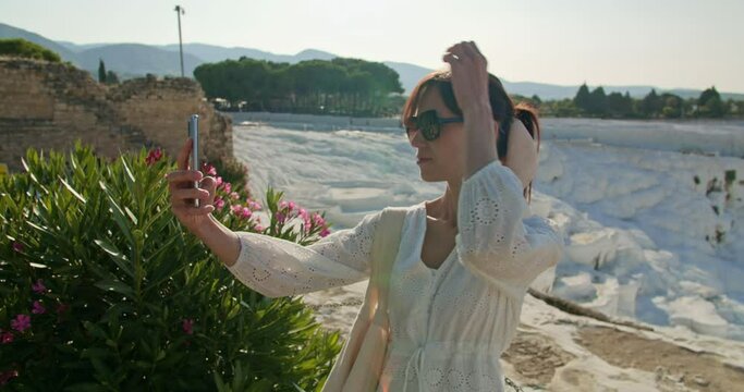 Female tourist take selfie photo on background of natural travertine pools and terraces in Pamukkale