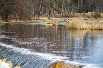 a man in a life jacket is standing in a river with a small boat in the background
