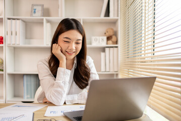 Woman using laptop to work or do homework at home with smiling face in her office, Creating happiness at work with a smile, Live performance or vdo call with laptop, Work from home.