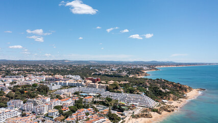 Fototapeta premium Aerial photo of the beautiful town in Albufeira in Portugal showing the Praia da Oura golden sandy beach, with hotels and apartment in the town, taken on a summers day in the summer time.