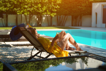 Woman with white wine relaxing by the pool.