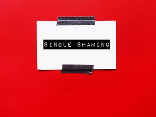 Paper stick on copy space red wall, with text SINGLE SHAMING, concept of being shamed or asked...