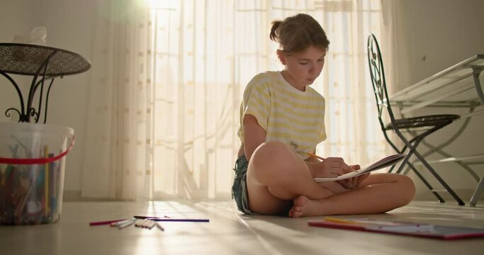 The child is engaged in art and draws at home sitting on the floor. A creative child works at home. High quality 4k footage