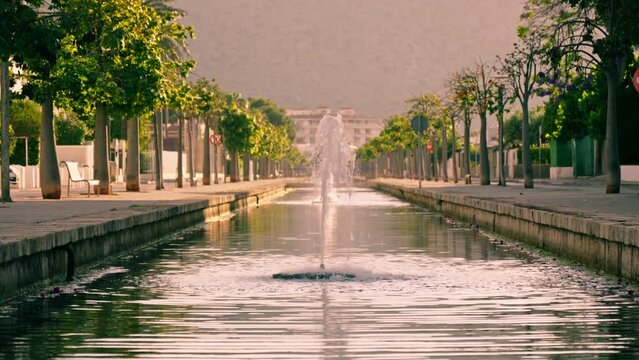 Fountain in a long canal against the background of an alley and mountains