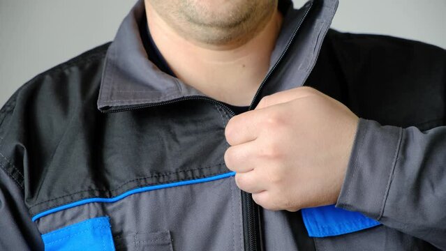 A man fastens a zipper on protective overalls, close-up