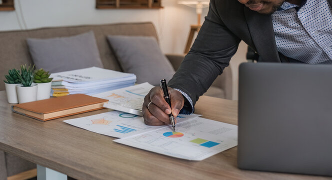 Data analysis and business statistics concept, african american businessman using laptop analyzing work result infographic stats graphs and charts, making report or strategic planning