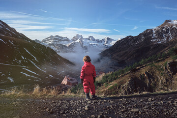 Kid on mountain slope near valley