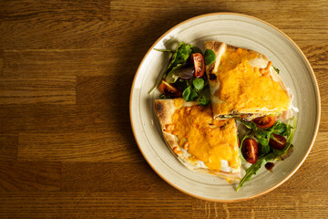 Ham and cheese tortilla sandwich with vegetables on a wooden table