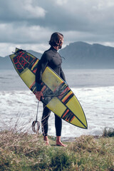 Fit male surfer admiring wavy sea after surfing