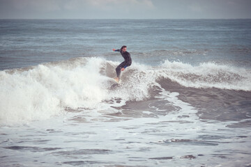 Man surfer riding wave on surfboard in stormy sea