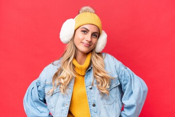 Young pretty Uruguayan woman wearing winter muffs isolated on red background background posing with...