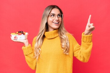 Young pretty Uruguayan woman holding a bowl of fruit isolated on red background pointing up a great idea