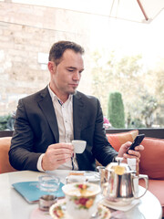 Serious businessman browsing smartphone in cafe
