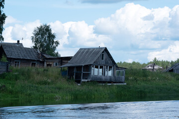 Fototapeta na wymiar derelict village on the river bank, abandoned wooden houses with empty windows