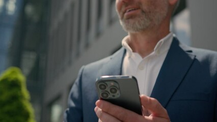Happy smiling mature employer middle-aged senior Caucasian entrepreneur outdoors old business man looking to side smile typing scrolling at mobile phone male businessman in city browsing smartphone