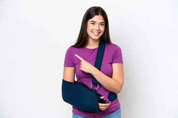 Young Brazilian woman with broken arm and wearing a sling isolated on white background pointing to...