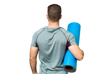 Young sport man going to yoga classes while holding a mat over isolated chroma key background in...