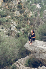 Woman sitting on boulder in highlands