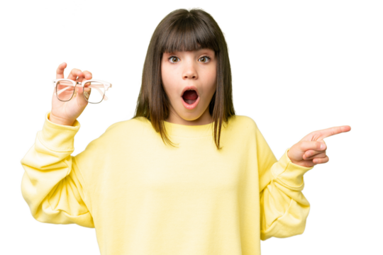 Little girl with glasses over isolated chroma key background surprised and pointing side