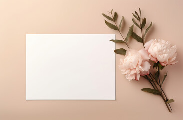 A blank white horizontal paper card positioned next to a delicate arrangement of pink peonies and green leaves on a pastel background. For invitations, announcements, or greeting cards.