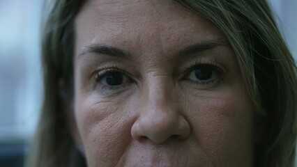 Mature woman macro close-up eyes staring at camera with serious expression. 50s female caucasian...