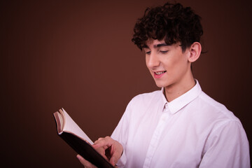 Funny young guy posing in the studio on a brown background. Study and work.