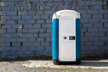 Portable mobile toilet. Temporary restroom, sanitation facility. Copy space on a brick wall.