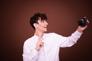Funny young guy posing in the studio on a brown background.