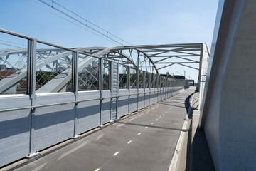 Pedestrian and bicycle footbridge along the railway bridge, connecting Grzegórzki with Zabłocie in Krakow, Poland. Train viaduct and walkway spanning over the Vistula River in Cracow, Wisła Kraków.